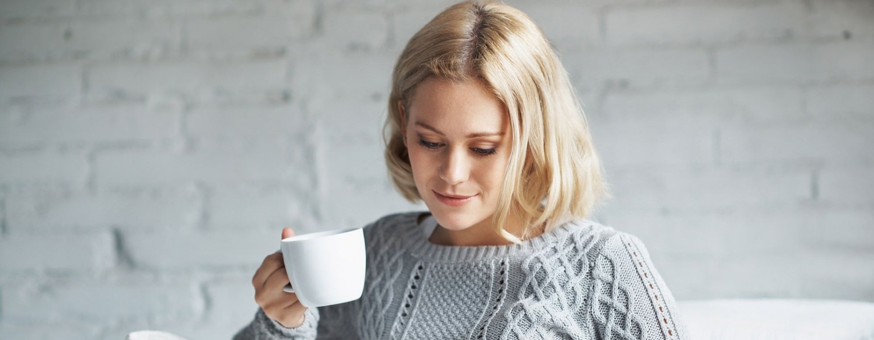 a person sitting down holding a cup looking at a tablet
